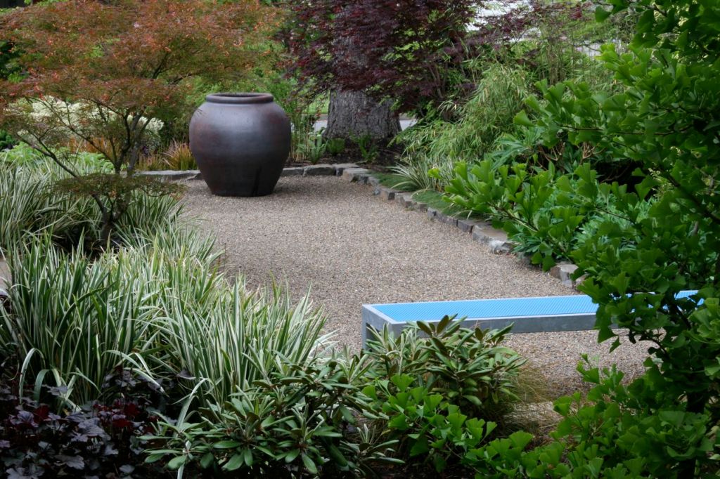 A custom metal bench anchors one end of this simple, pea gravel terrace.
